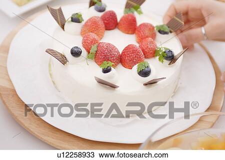 Stock Image - Strawberry cake and a woman's hand. Fotosearch