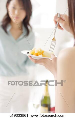 Two young women eating at party View Large Photo Image Stock Image - Two young women eating at party. Fotosearch