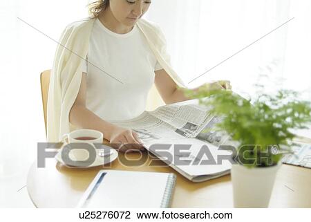 Stock Image - Young woman reading newspaper. Fotosearch