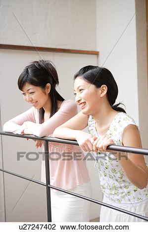 Two young women leaning on railing View Large Photo Image Stock Image - Two young women leaning on railing. Fotosearch
