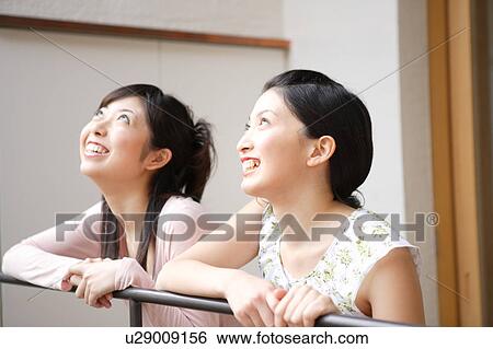 Two young women looking up View Large Photo Image Stock Photograph - Two young women looking up. Fotosearch