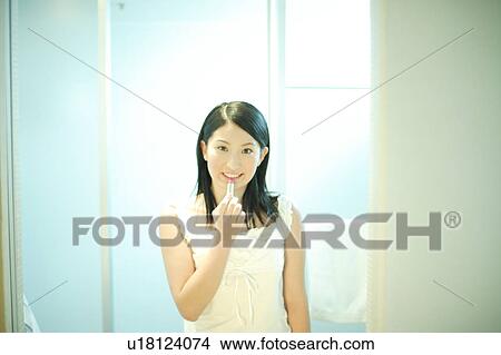 Young woman applying lipstick View Large Photo Image Picture - Young woman applying lipstick. Fotosearch