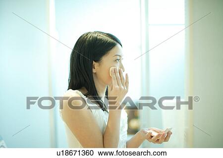 Stock Image - Young woman applying make-up. Fotosearch