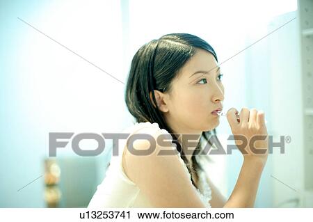 Stock Image - Young woman brushing teeth. Fotosearch
