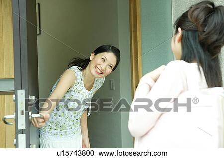Young woman greeting her friend at entrance View Large Photo Image Stock Image - Young woman greeting her friend at entrance. Fotosearch