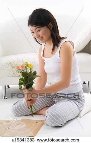 Stock Image - Young woman holding flowers. Fotosearch