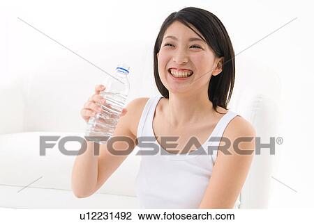 Stock Image - Young woman holding water bottle. Fotosearch