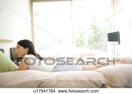 Picture - Young woman lying on bed. Fotosearch