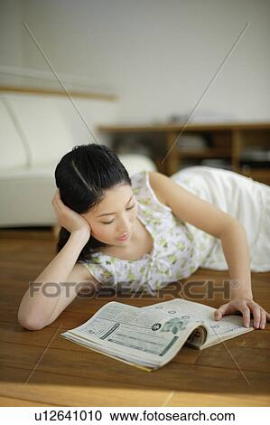 Young woman lying on floor and reading magazine View Large Photo Image Stock Image - Young woman lying on floor and reading magazine. Fotosearch