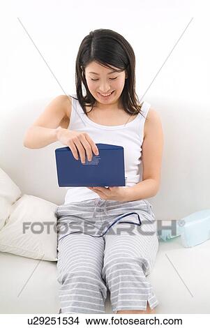 Picture - Young woman opening gift. Fotosearch