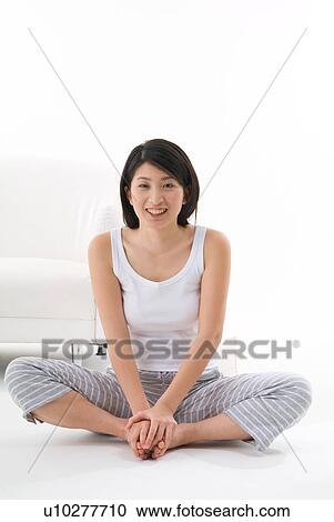 Stock Image - Young woman sitting on floor. Fotosearch