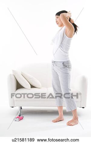 Stock Photo - Young woman tying up her hair. Fotosearch