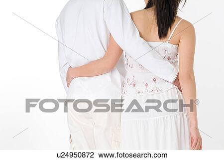 Rear view of young couple standing with arms around View Large Photo Image Stock Image - Rear view of young couple standing with arms around. Fotosearch