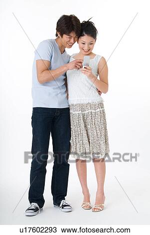 Stock Image - Young couple looking at mobile phone. Fotosearch