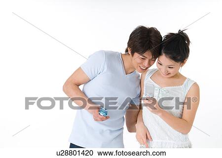 Young couple looking at mobile phone View Large Photo Image Stock Image - Young couple looking at mobile phone. Fotosearch