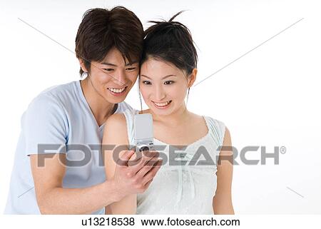 Stock Photo - Young couple looking at mobile phone. Fotosearch
