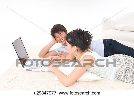 Young couple lying on floor and using laptop computer View Large Photo Image Stock Photo - Young couple lying on floor and using laptop computer. Fotosearch
