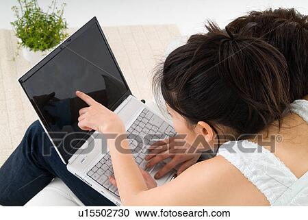 Stock Image - Young couple sitting and looking at laptop computer. Fotosearch