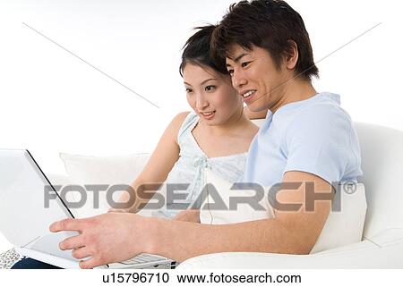 Stock Image - Young couple sitting and looking at laptop computer. Fotosearch