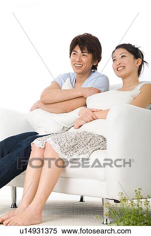 Young couple sitting on sofa View Large Photo Image Stock Photography - Young couple sitting on sofa. Fotosearch