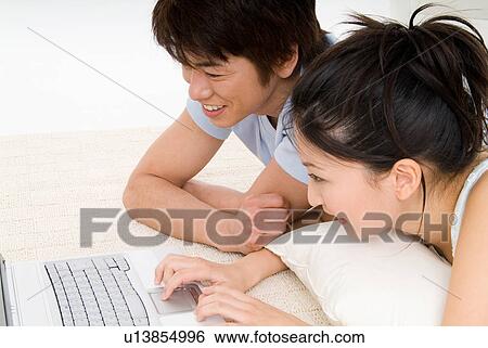 Stock Photograph - Young couple using laptop computer. Fotosearch