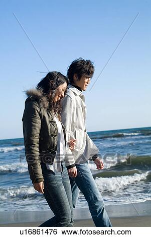 Stock Photograph - Young couple walking in a beach. Fotosearch