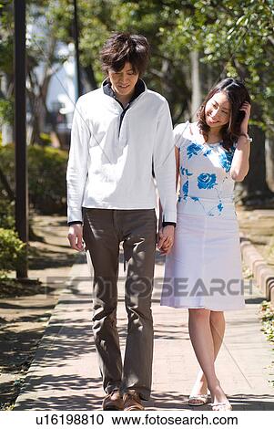 Stock Image - Young couple walking in a park. Fotosearch
