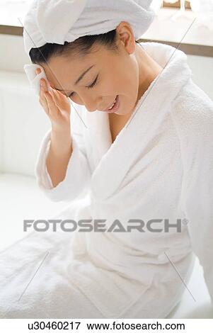 Stock Photo - A mid adult woman applying moisturizer. Fotosearch