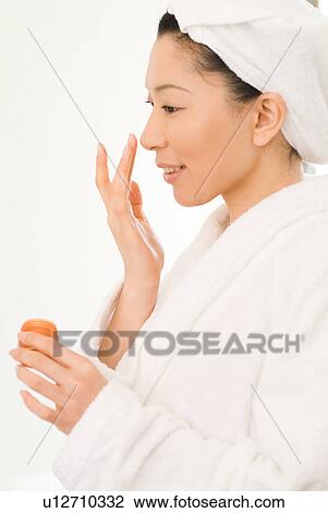 A mid adult woman in bathrobe applying moisturizer View Large Photo Image Stock Image - A mid adult woman in bathrobe applying moisturizer. Fotosearch