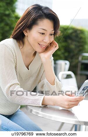 Stock Photo - A mid adult woman looking at mobile phone. Fotosearch