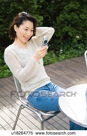 Stock Photography - A mid adult woman looking at mobile phone. Fotosearch