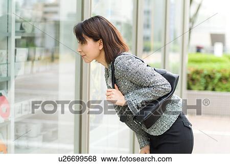Stock Photo - A mid adult woman looking into shop window. Fotosearch