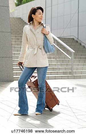 A mid adult woman pulling suitcase View Large Photo Image Stock Photo - A mid adult woman pulling suitcase. Fotosearch