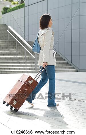 A mid adult woman pulling suitcase View Large Photo Image Stock Photograph - A mid adult woman pulling suitcase. Fotosearch
