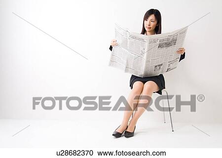 Stock Image - A mid adult woman reading newspaper. Fotosearch