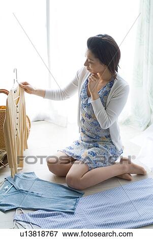Stock Photo - A mid adult woman selecting clothes. Fotosearch