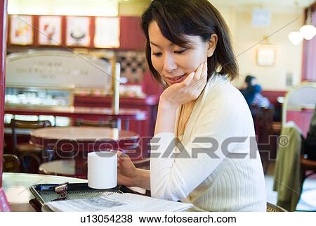 A mid adult woman sitting in a coffee shop View Large Photo Image Stock Photo - A mid adult woman sitting in a coffee shop. Fotosearch