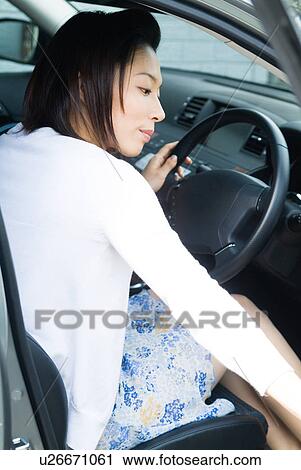 Stock Image - A mid adult woman sitting in driver's seat. Fotosearch