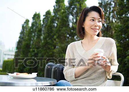 Stock Photograph - A mid adult woman sitting in outdoor chair. Fotosearch