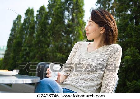 A mid adult woman sitting in outdoor chair View Large Photo Image Stock Photograph - A mid adult woman sitting in outdoor chair. Fotosearch
