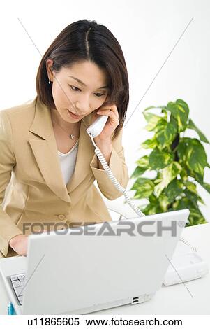 Stock Photography - A mid adult woman talking over phone. Fotosearch
