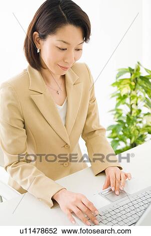 Stock Image - A mid adult woman using computer. Fotosearch