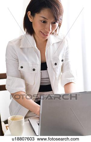 Stock Image - A mid adult woman using computer. Fotosearch