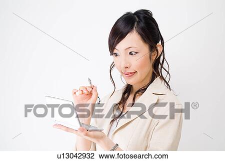 Stock Image - A mid adult woman using electronic dictionary. Fotosearch
