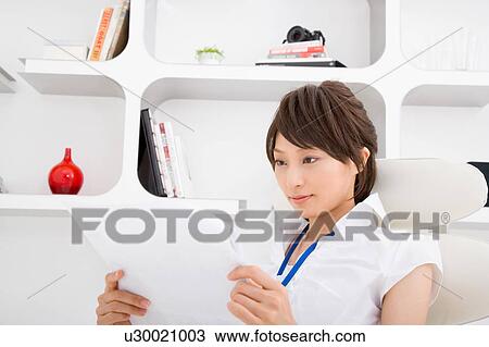 Stock Image - A young woman reading document. Fotosearch