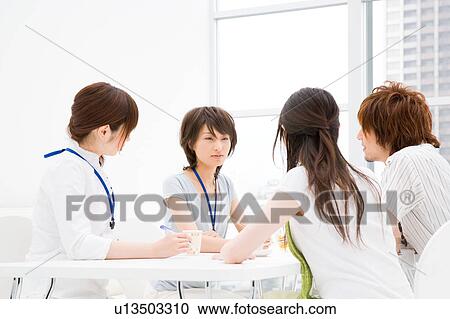 Stock Image - Four people meeting at table. Fotosearch