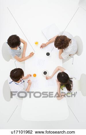 Stock Image - Four people meeting at table. Fotosearch
