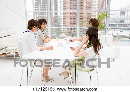 Stock Photography - Four people meeting at table. Fotosearch