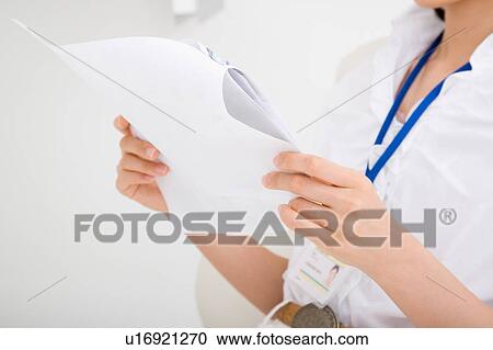 Stock Image - Midsection of a young woman reading document. Fotosearch
