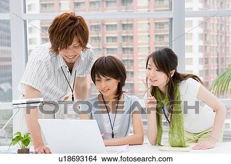 Picture - Three people looking at computer. Fotosearch